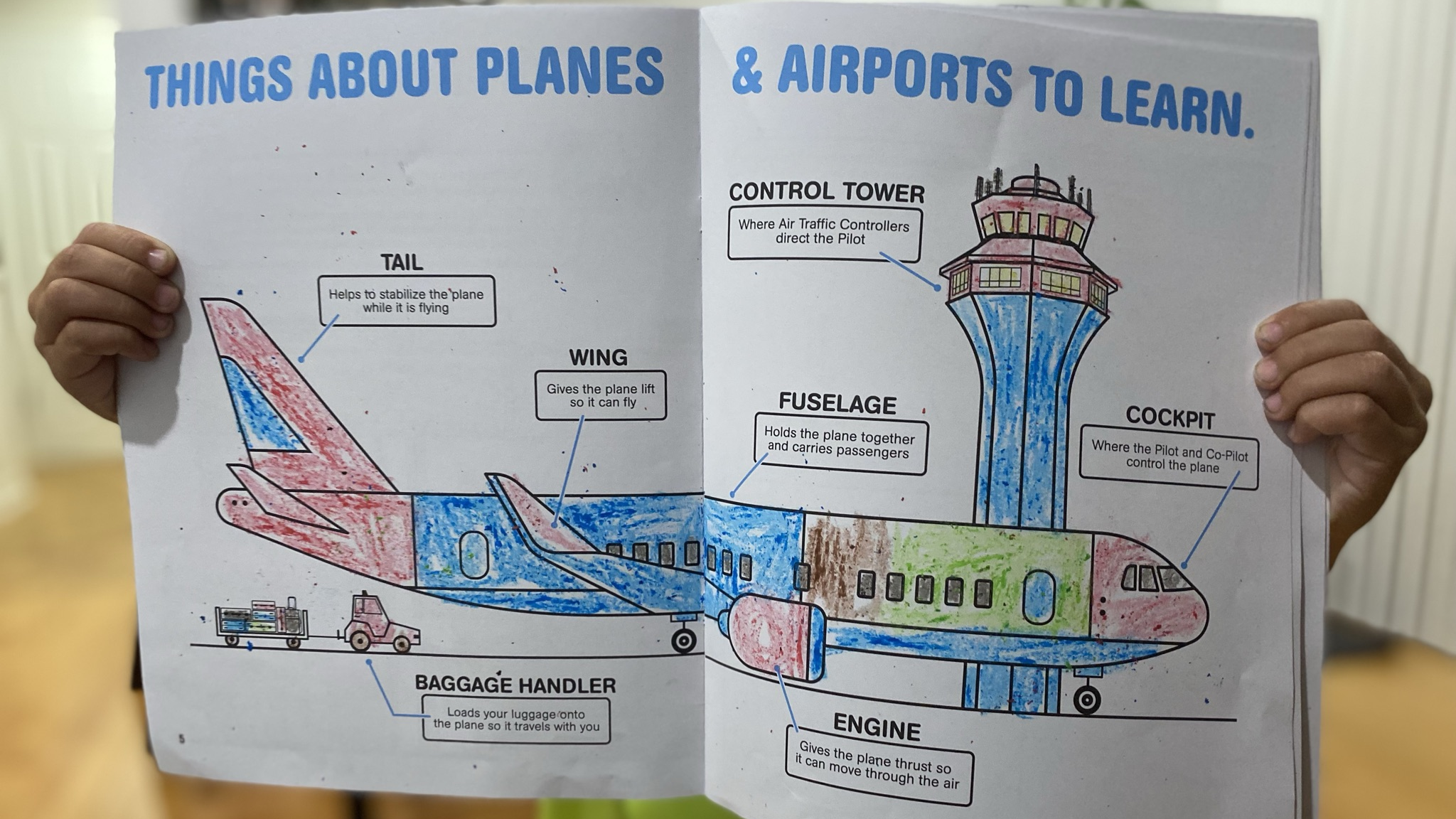Child holding an illustrated Jr. Flight Crew activity book about planes and airports